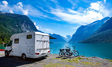 Wohnmobil und Fahrräder stehen am Seeufer vor alpinen Bergpanorama